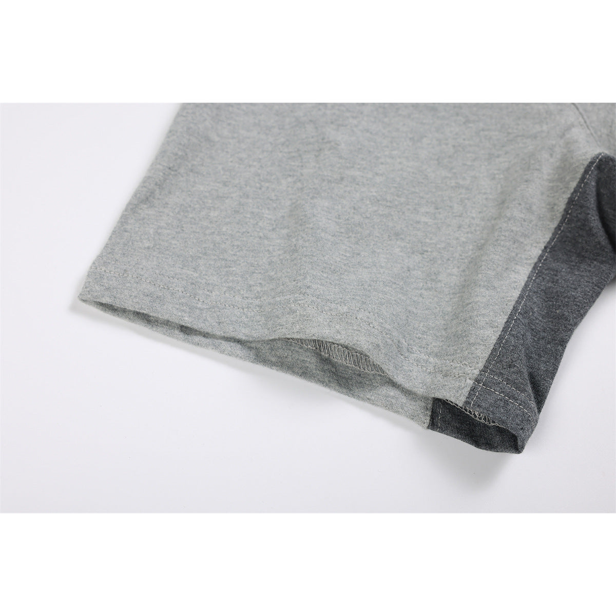 Close-up of a gray short sleeve and its seam beside a dark gray contrasting panel.
