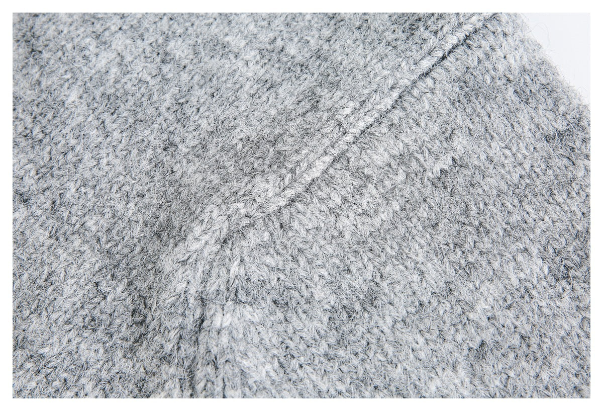 Close-up of light gray marled knit fabric showing a diagonal knitted seam.