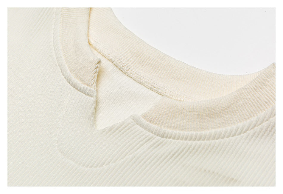 Close-up of the ivory top's ribbed crew neckline and shoulder seam.