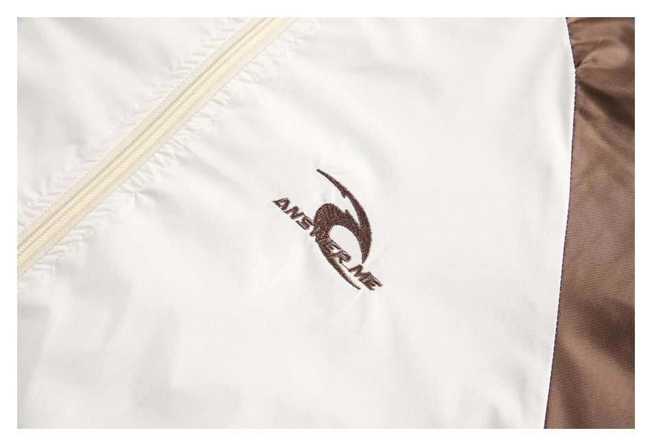 Close-up of a brown embroidered logo on the white panel of a jacket.