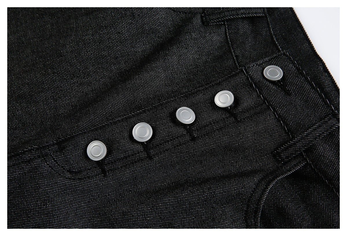Close-up of black jeans showing several silver buttons along the front fly and waistband.