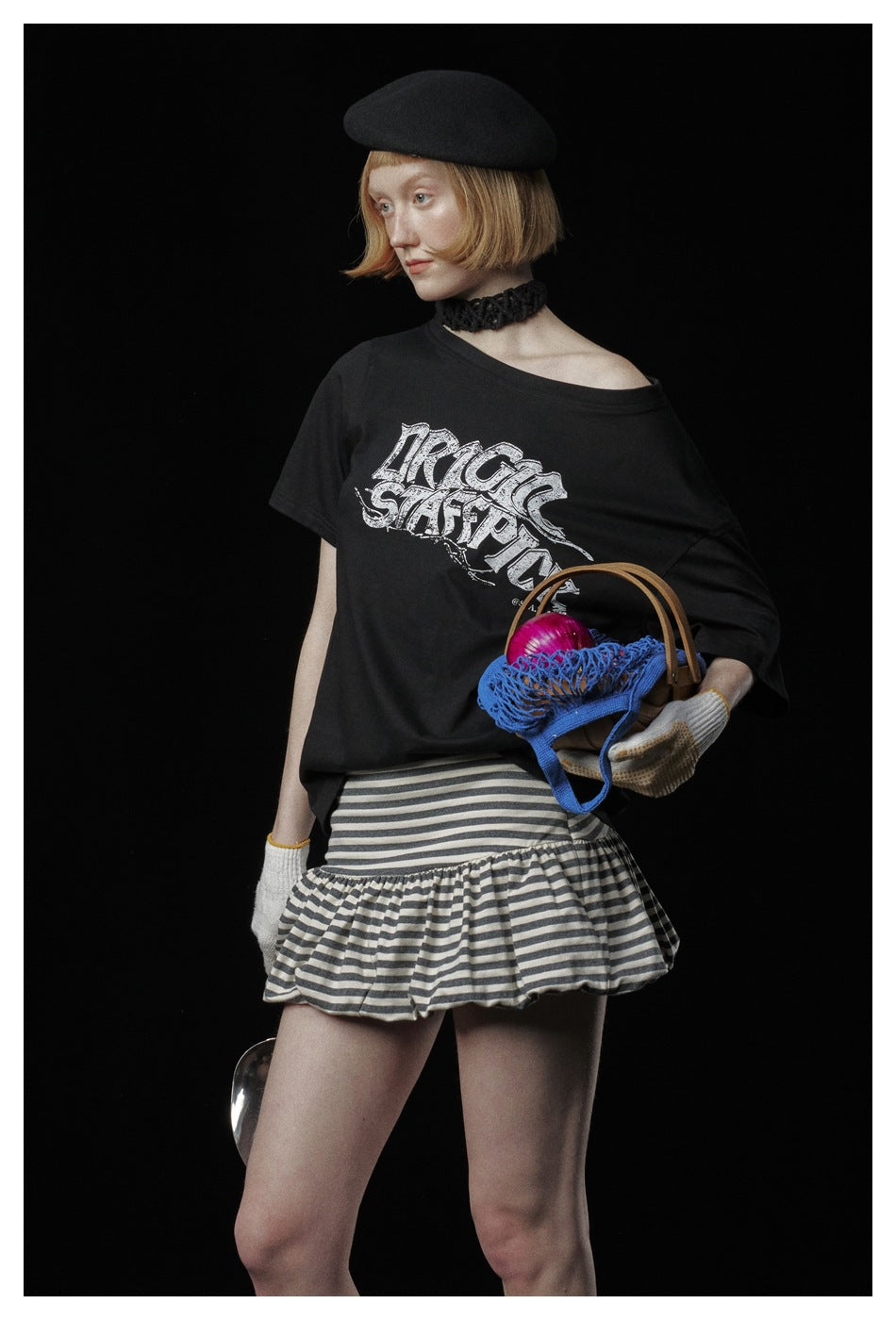 Close view of a model in a black graphic T-shirt and gray-and-black striped ruffle skirt.
