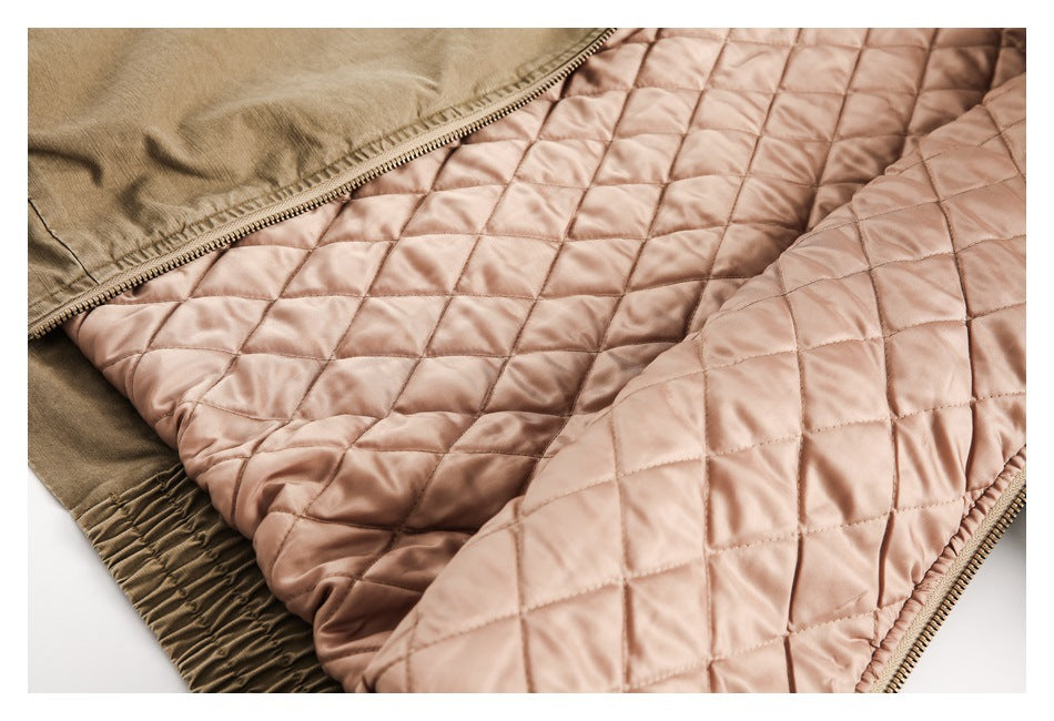 Close-up of a dusty pink diamond-quilted lining beside olive fabric, with a zipper and gathered edge.