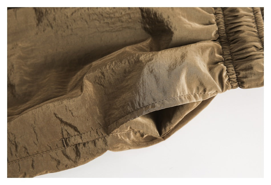 Close-up of a stitched seam and gathered waistband on brown shorts.
