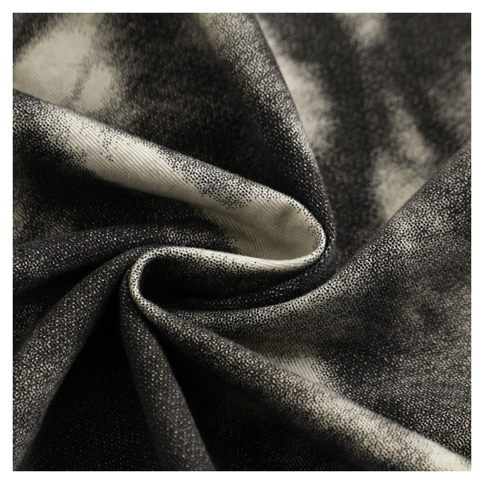 Macro view of the black and cream abstract-patterned garment fabric, shown draped in soft folds.