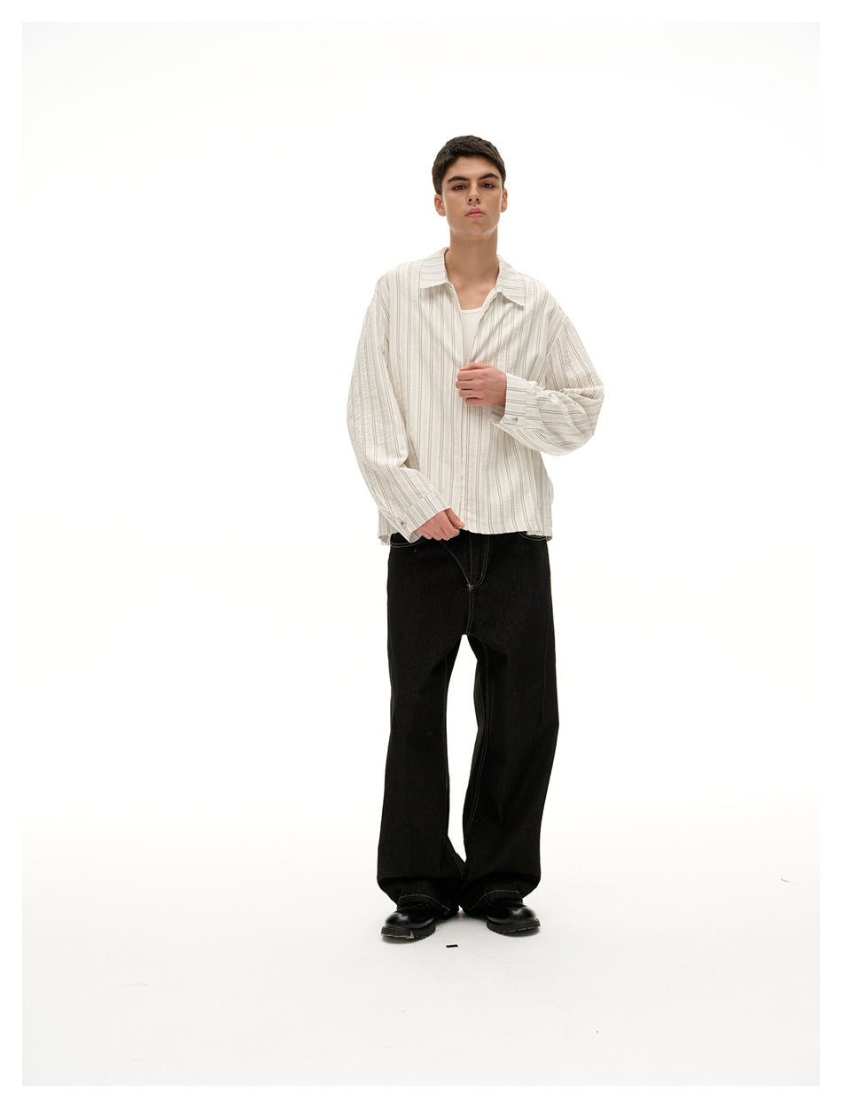 Front view of a model in a cream shirt with fine vertical stripes, worn with black trousers.