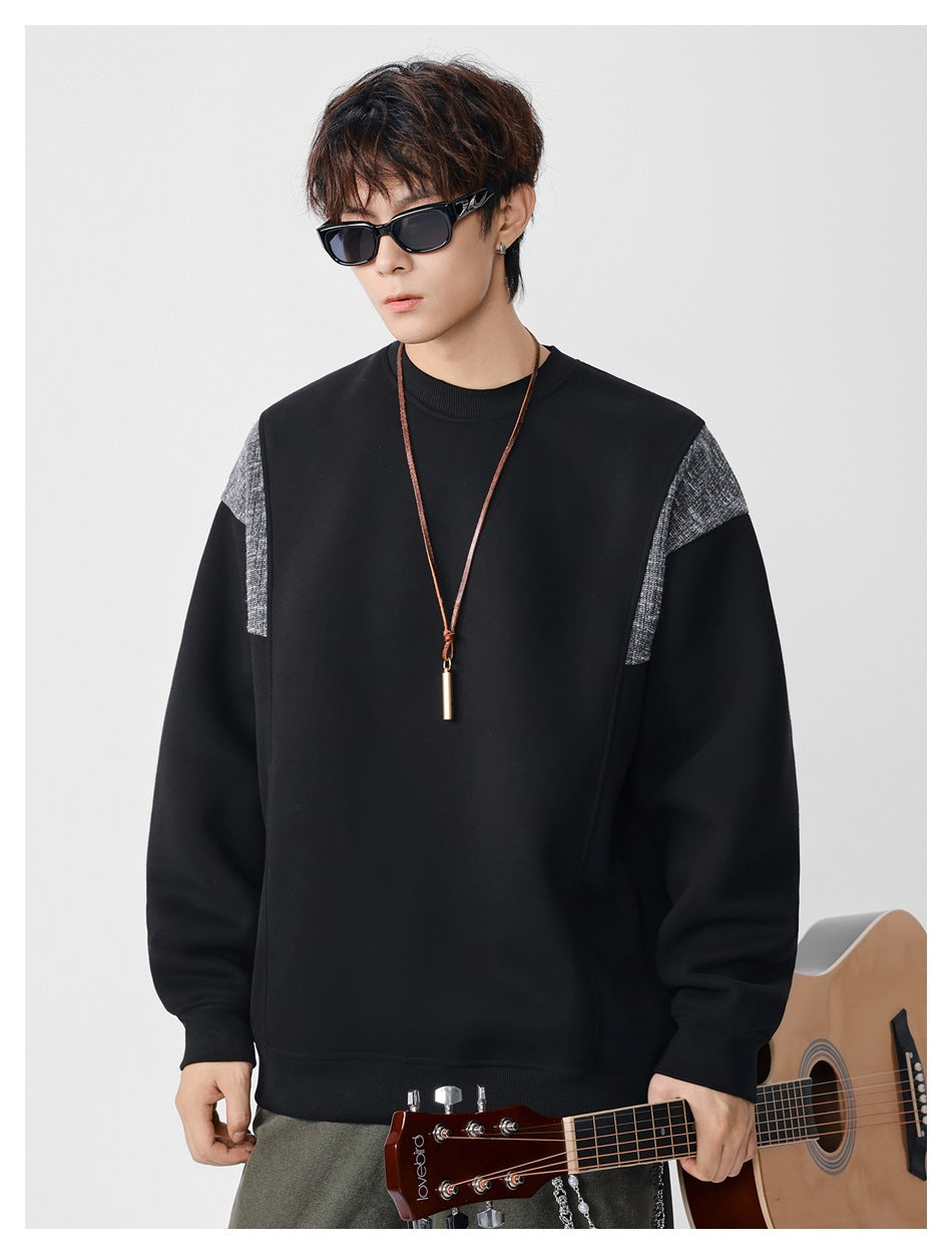 Model wearing a black crewneck sweatshirt with textured gray shoulder panels and ribbed trim.