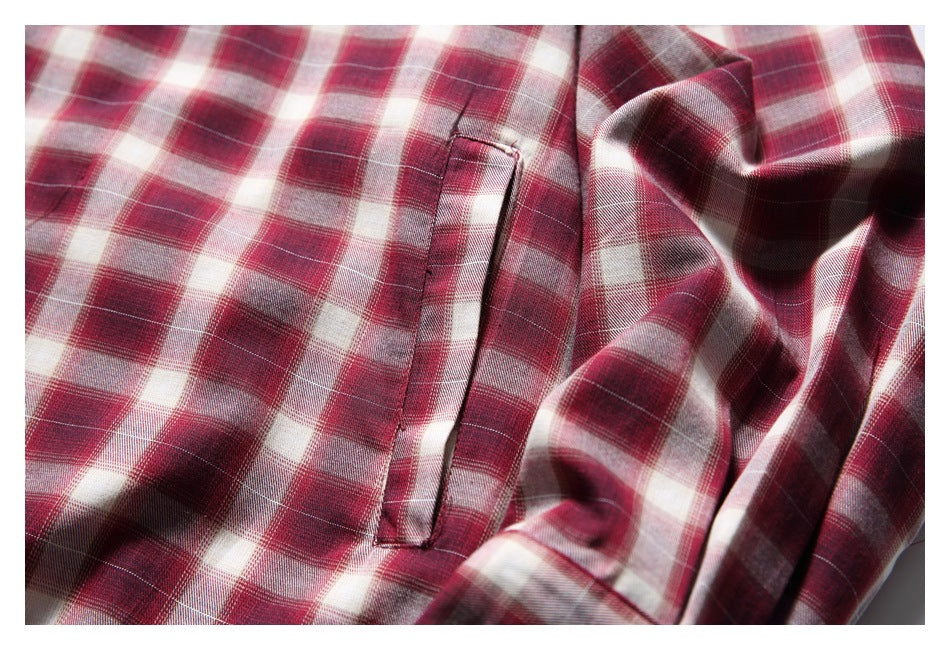 Close-up of a narrow welt pocket on a red, burgundy, and cream plaid shirt.