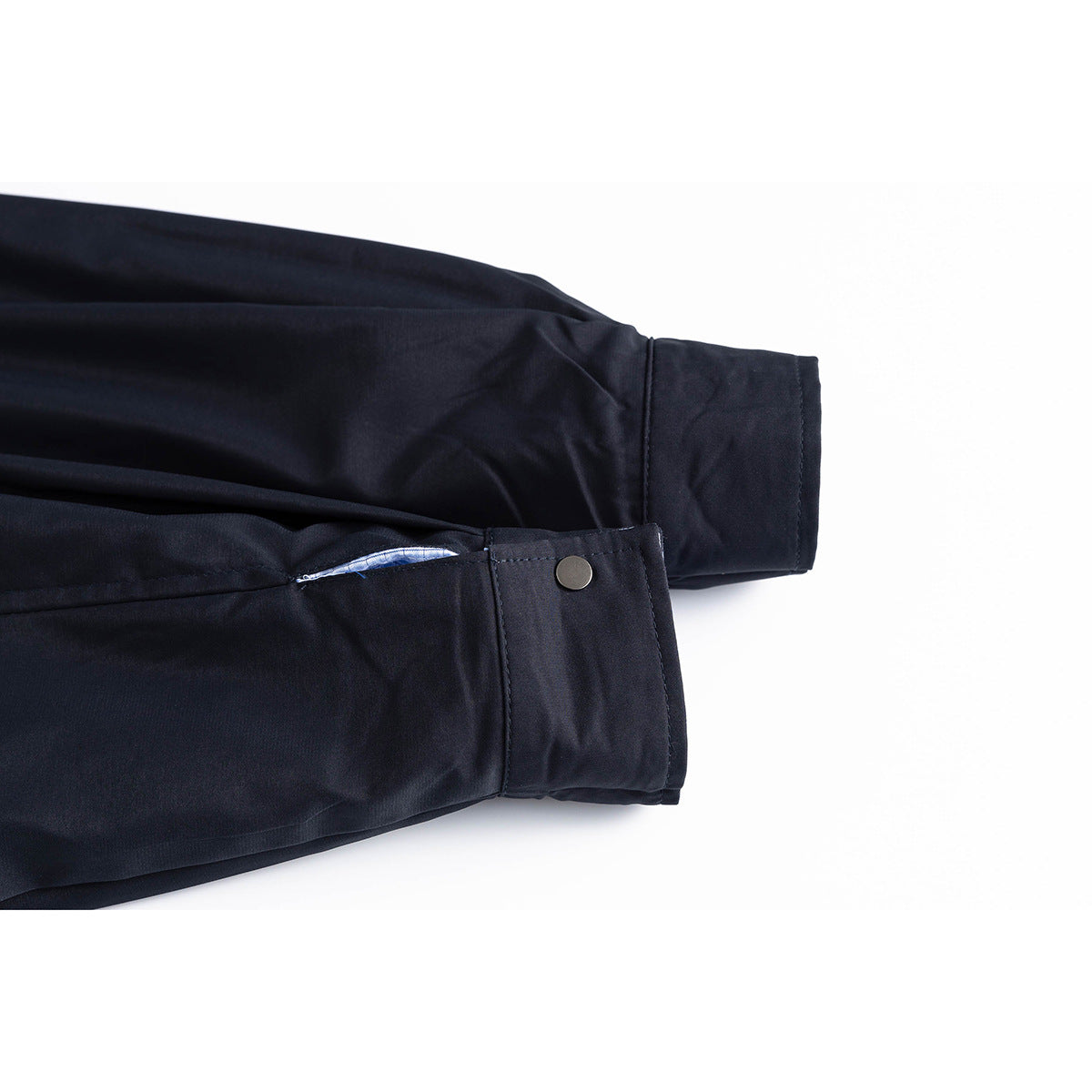 Close-up of a navy jacket sleeve cuff with a button and a glimpse of blue checked lining.