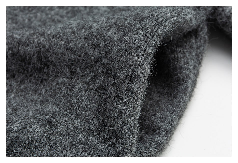 Close-up of a fuzzy charcoal-gray knit garment edge against a white background.