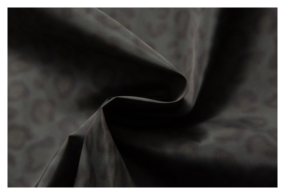Close-up of dark charcoal fabric folded into soft curves, showing a subtle surface sheen.