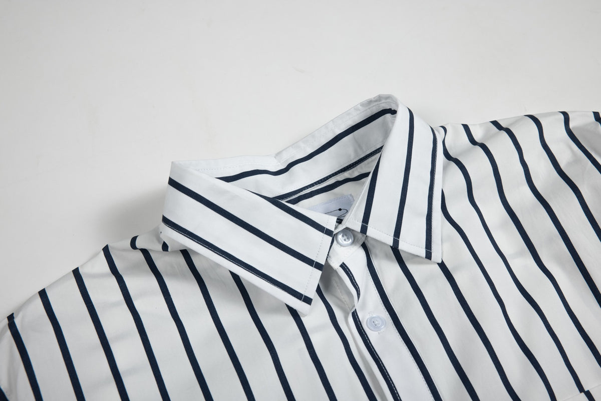 Close-up of a white shirt collar and button placket with bold navy stripes.