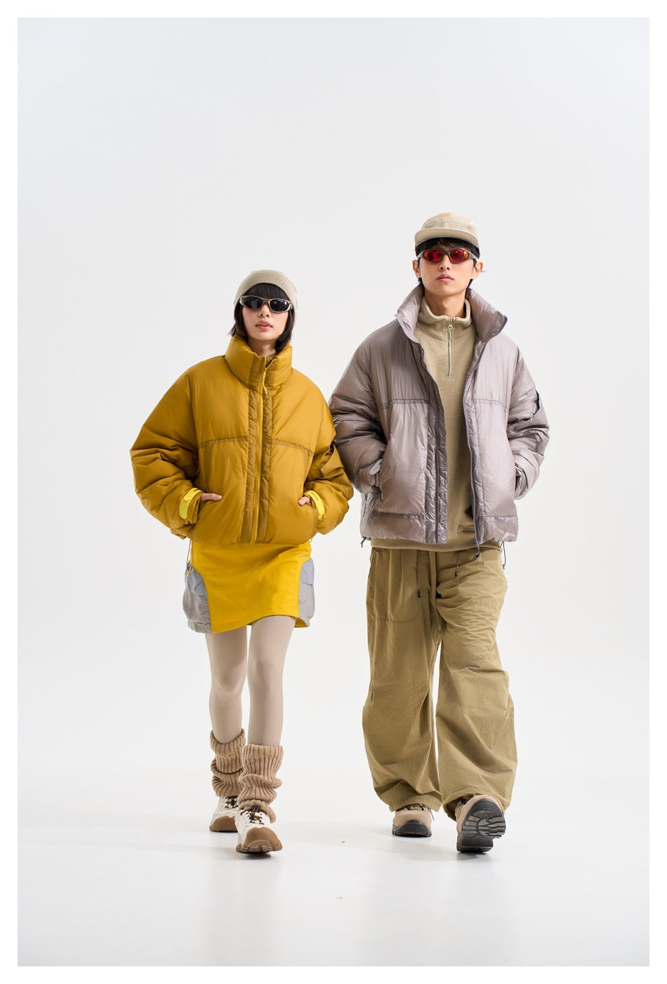 Two models wear a mustard puffer jacket and a taupe puffer jacket with casual outdoor-inspired outfits.