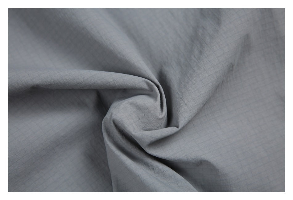 Close-up of gray fabric gathered into folds, showing a subtle fine grid texture.