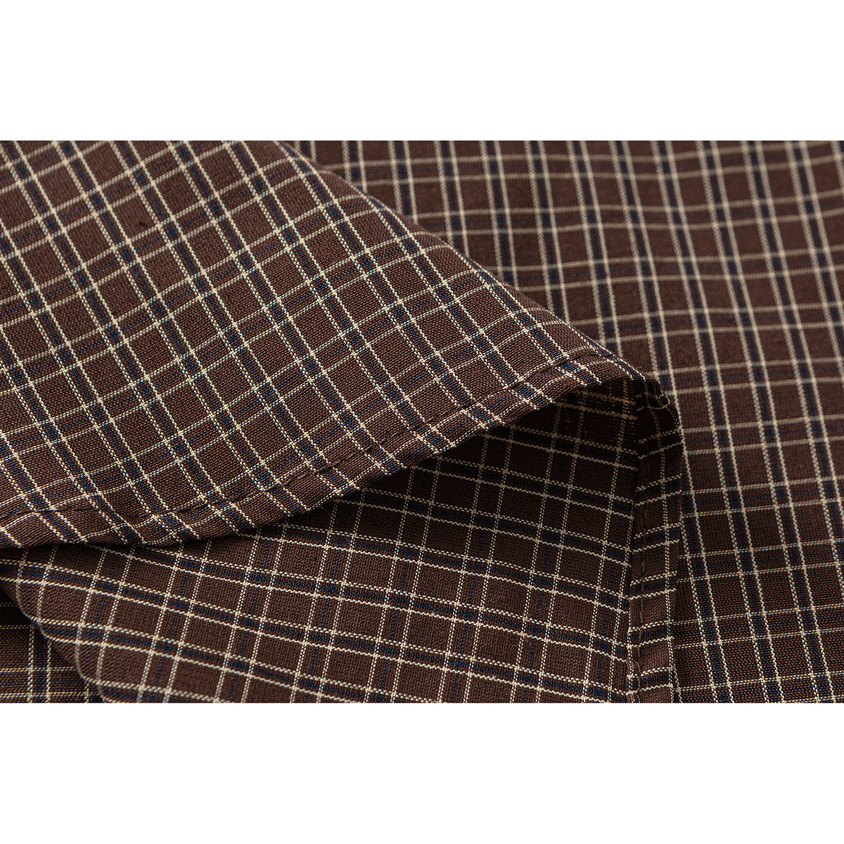 Close-up of brown plaid shirt fabric folded to show its fine checked pattern.