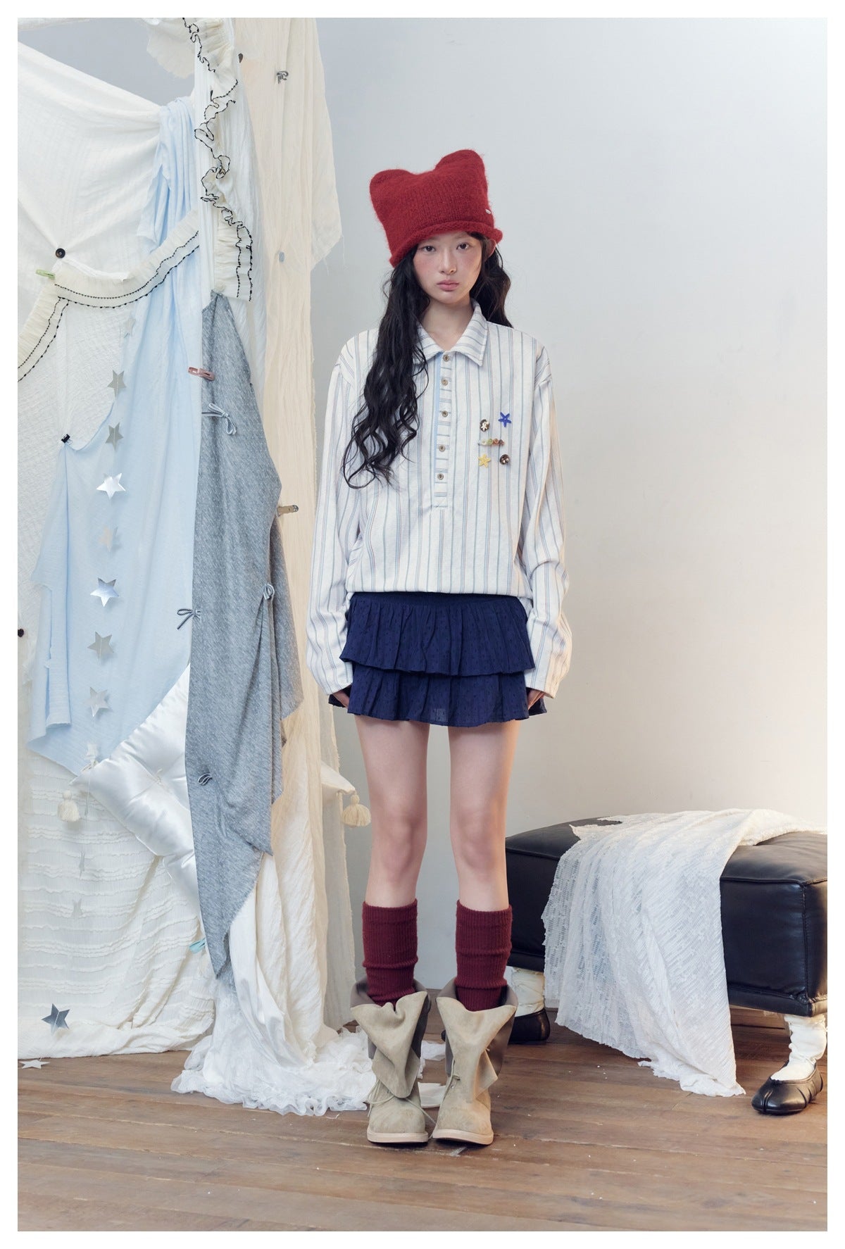 Front view of a model wearing a white fine-striped shirt with colorful charms and a navy tiered skirt.