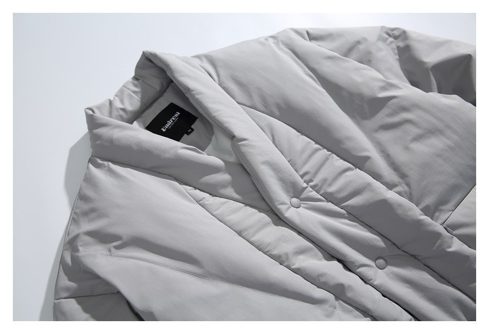 Close-up of a light gray padded jacket showing its folded collar, snap-button placket, and inside neck label.
