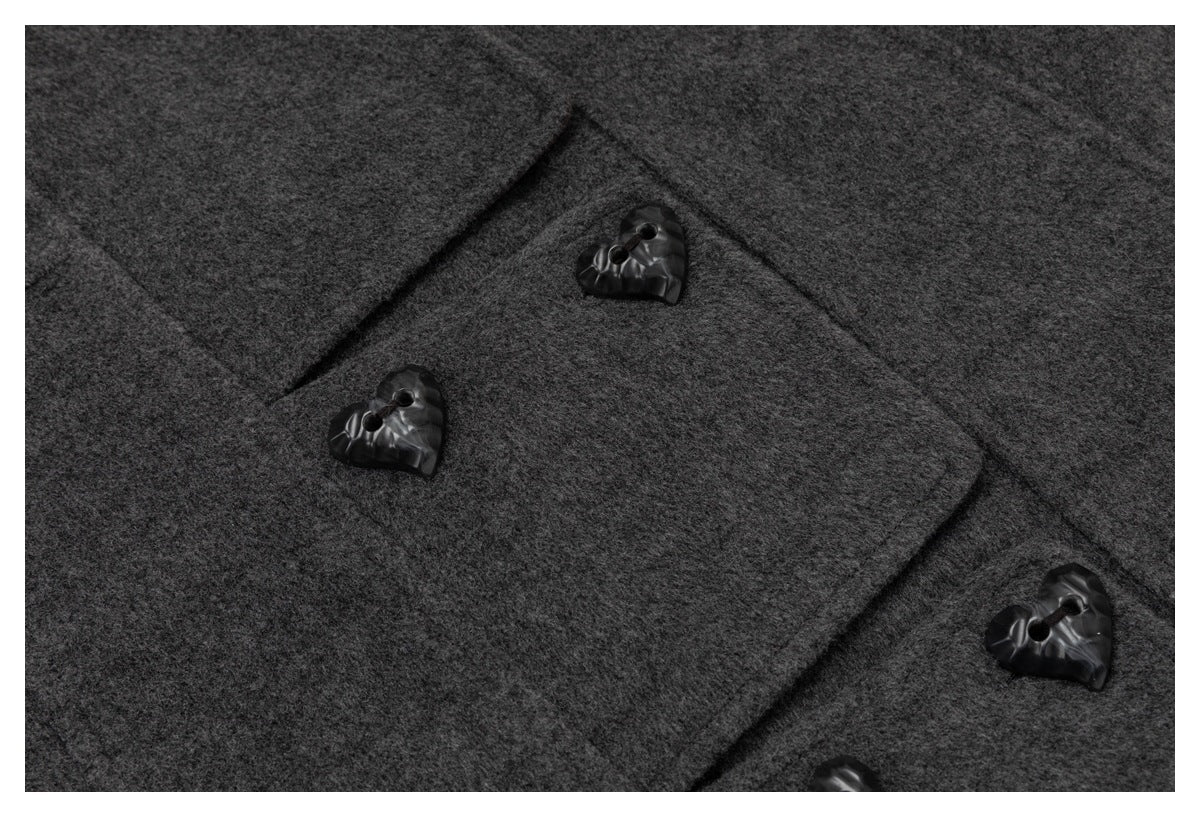 Close-up of a dark charcoal coat front with overlapping fabric panels and glossy black buttons.