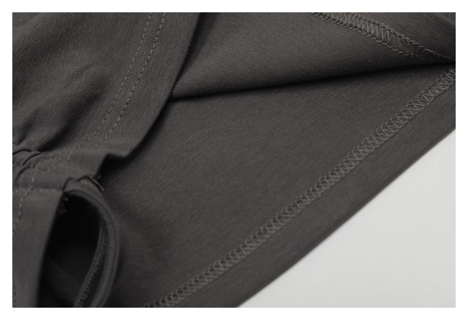 Close-up of dark charcoal garment fabric showing a stitched seam and overlocked hem.