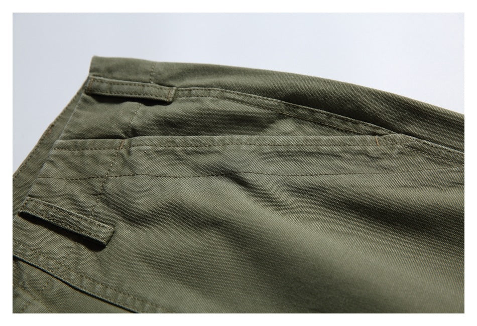 Close-up of olive trouser waistband and pocket stitching with fabric tabs.