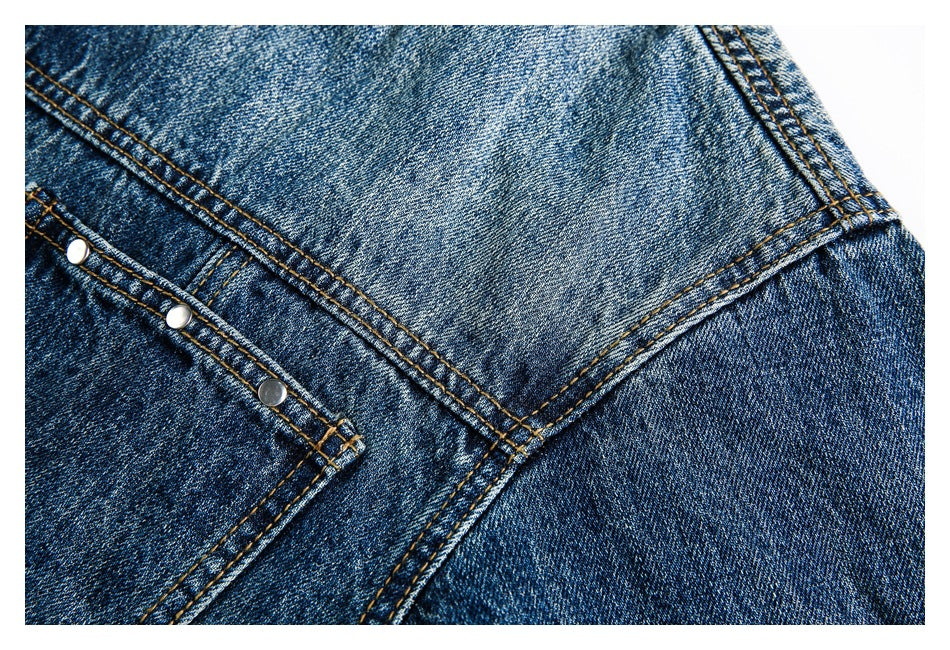 Close-up of blue denim with orange topstitching, a pocket corner and three metal rivets.