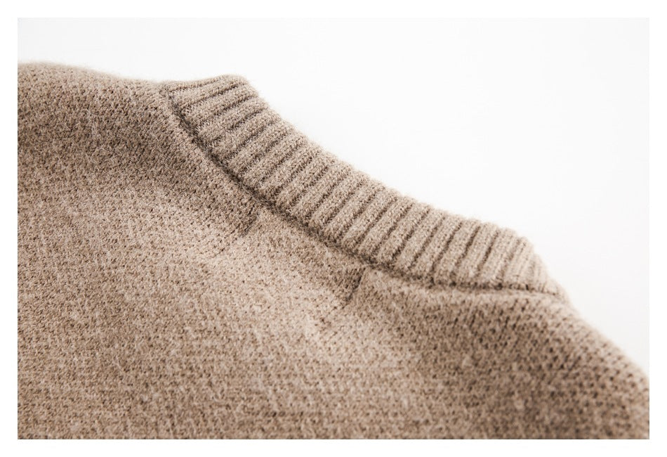 Close-up of a taupe-brown knit garment's ribbed neckline and textured body.
