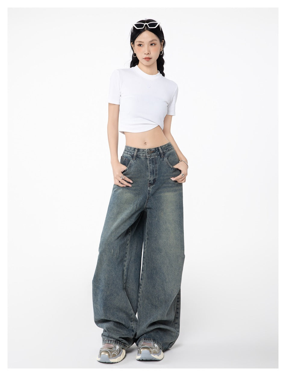 Model wearing light blue wide-leg jeans with a white cropped tee, hands in pockets, full-length front view