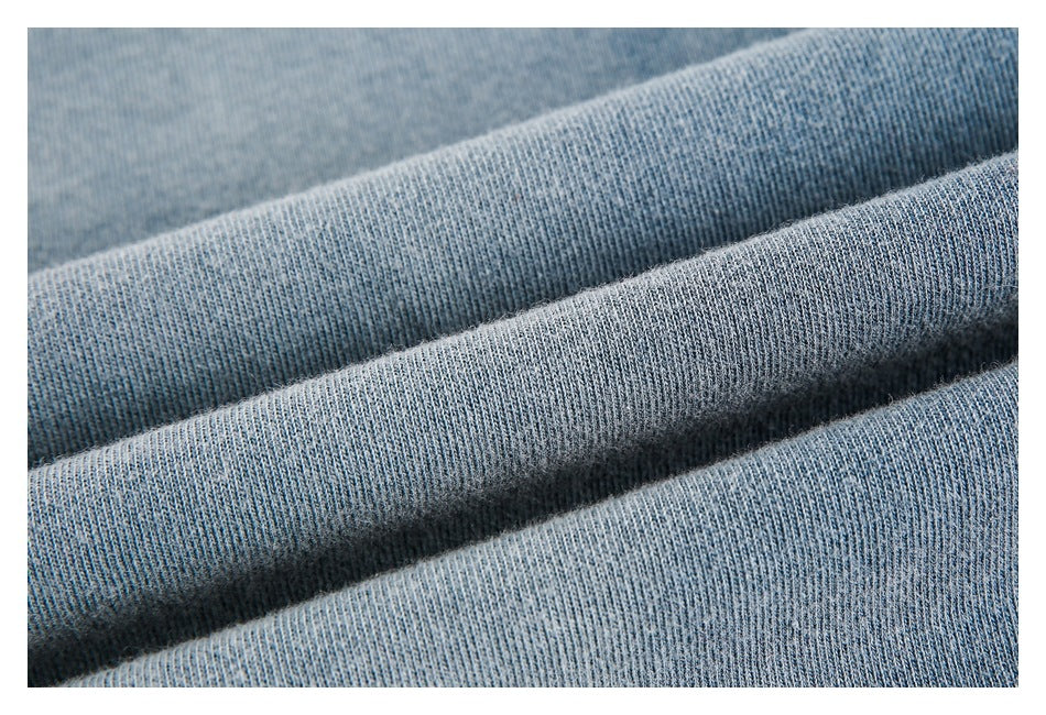 Macro view of blue-gray knit fabric arranged in soft folds, showing its textured surface.