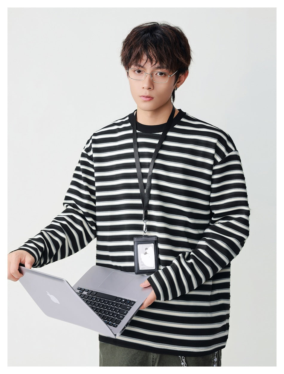 Model wearing an oversized black, gray, and white striped long-sleeve shirt with a black collar; front view.