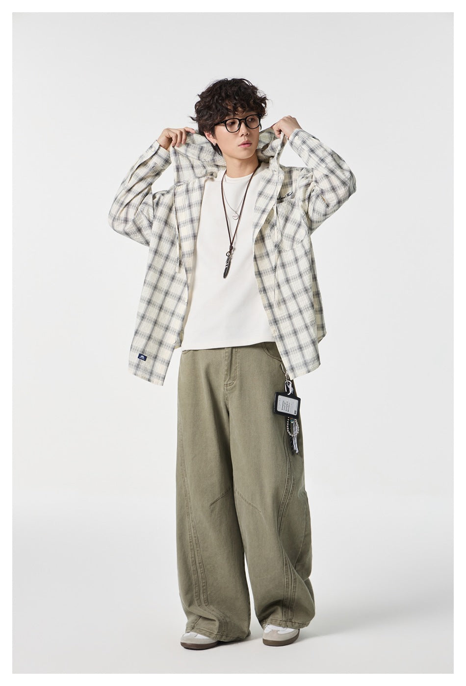 Model wearing a light gray plaid button-up shirt over a white tee, with the shirt held open at the collar.