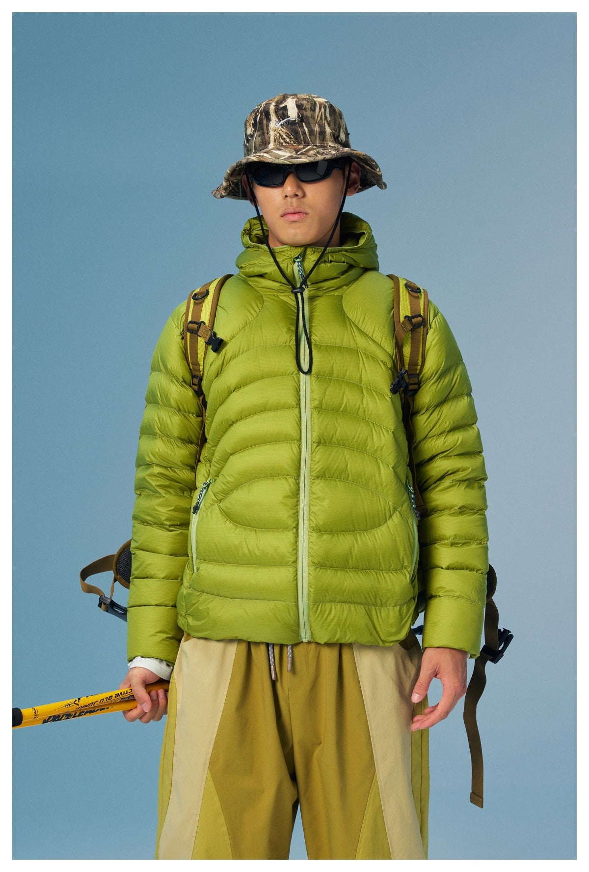 Front view of a model in a lime-green quilted jacket with a hood, zip front and zip pockets.