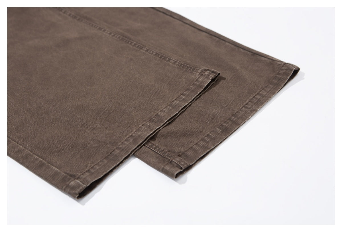 Close-up of the brown trousers' stitched leg hems and fabric texture.