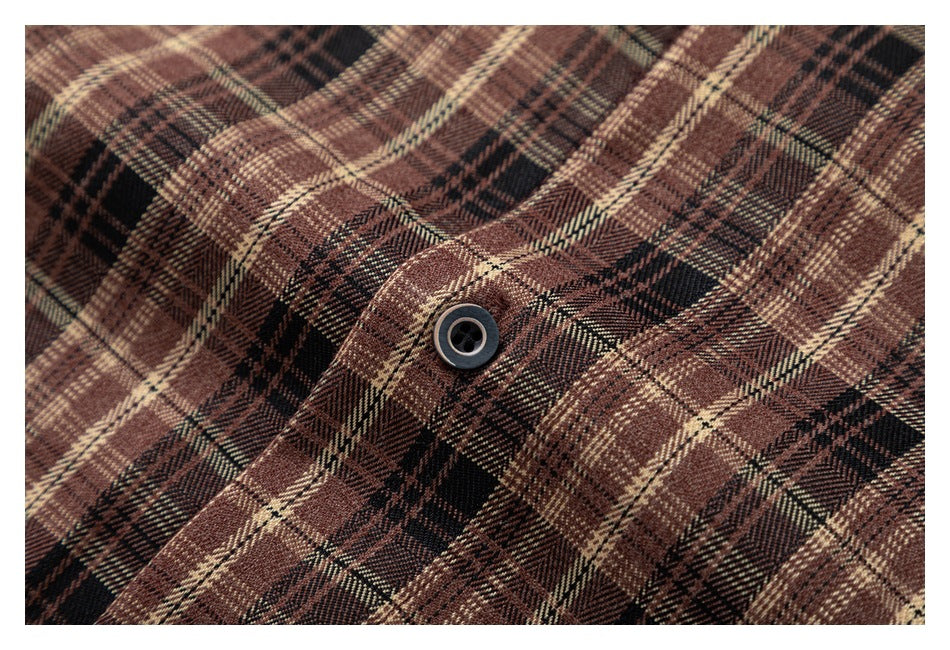 Close-up of a dark button on the brown plaid shirt fabric.