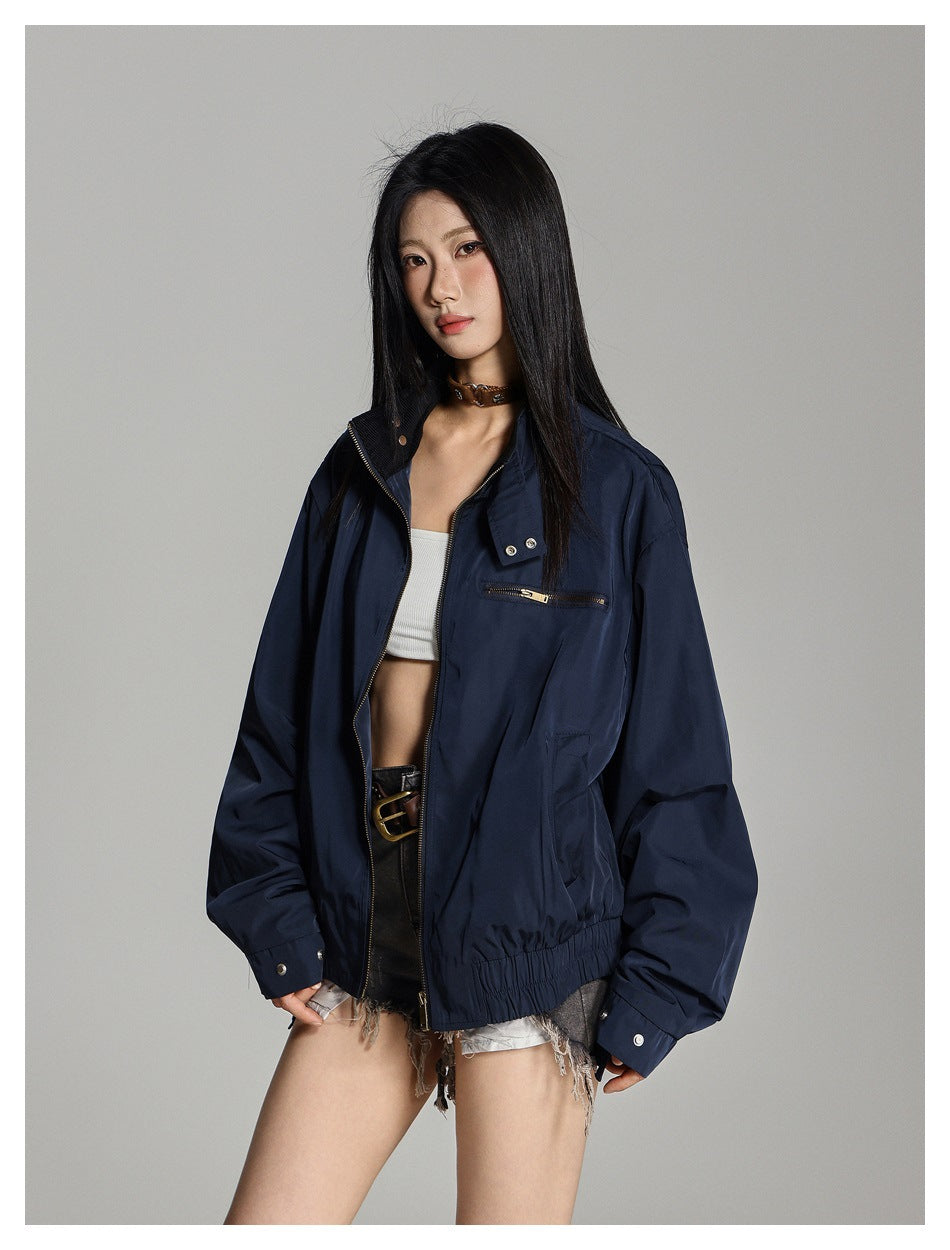 Model wearing an open navy jacket with a zip chest pocket, snap collar, and gathered hem.