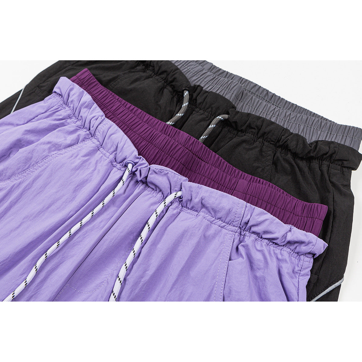 Close-up of lavender, black, and plum wide-leg pants showing elastic waistbands and drawstrings.