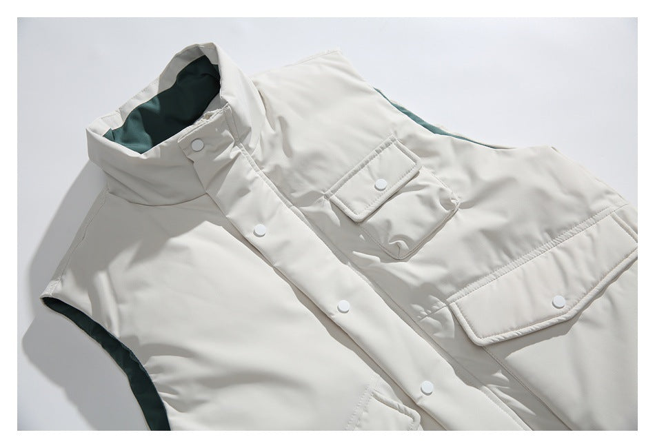 Angled close-up of the ivory vest showing its dark green lining, snap-button placket, and flap pockets.