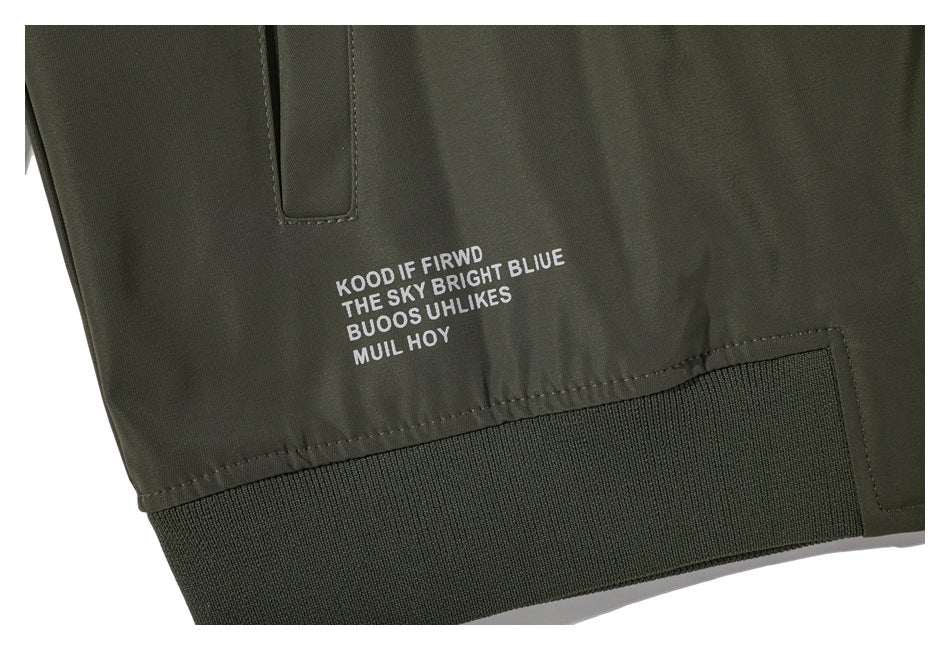 Close-up of an olive jacket hem with a ribbed band, snap placket, and small white printed text.