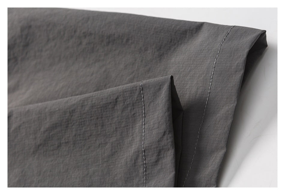 Close-up of charcoal gray garment fabric with a folded edge and contrast stitching.
