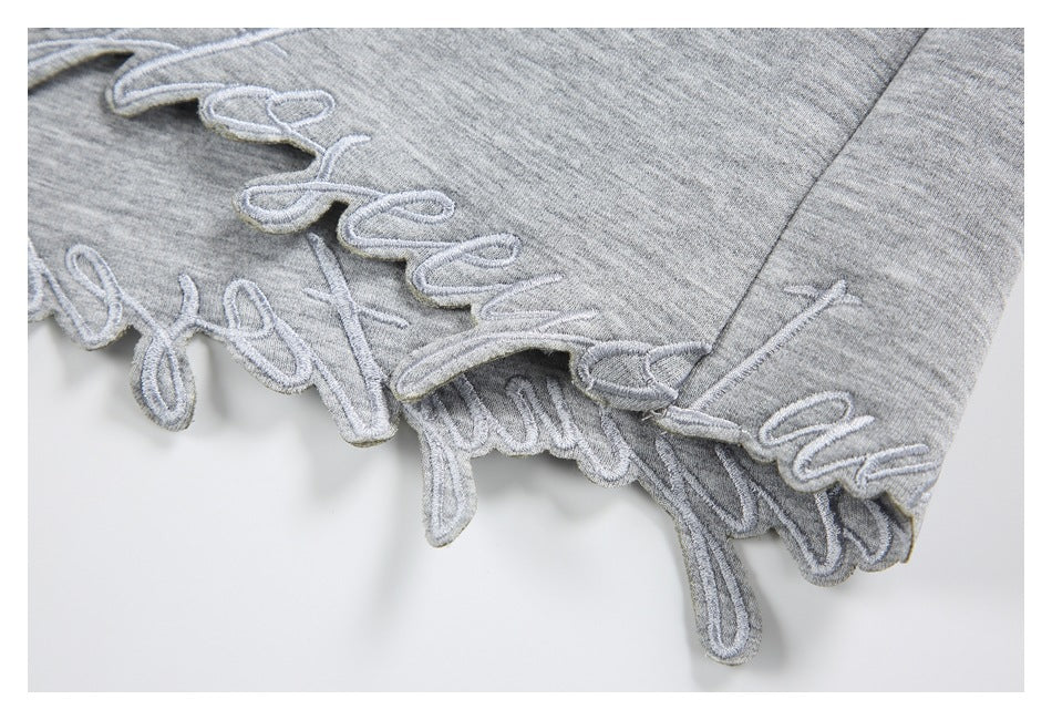 Close-up of raised script embroidery along the edge of a gray heather sweatshirt.