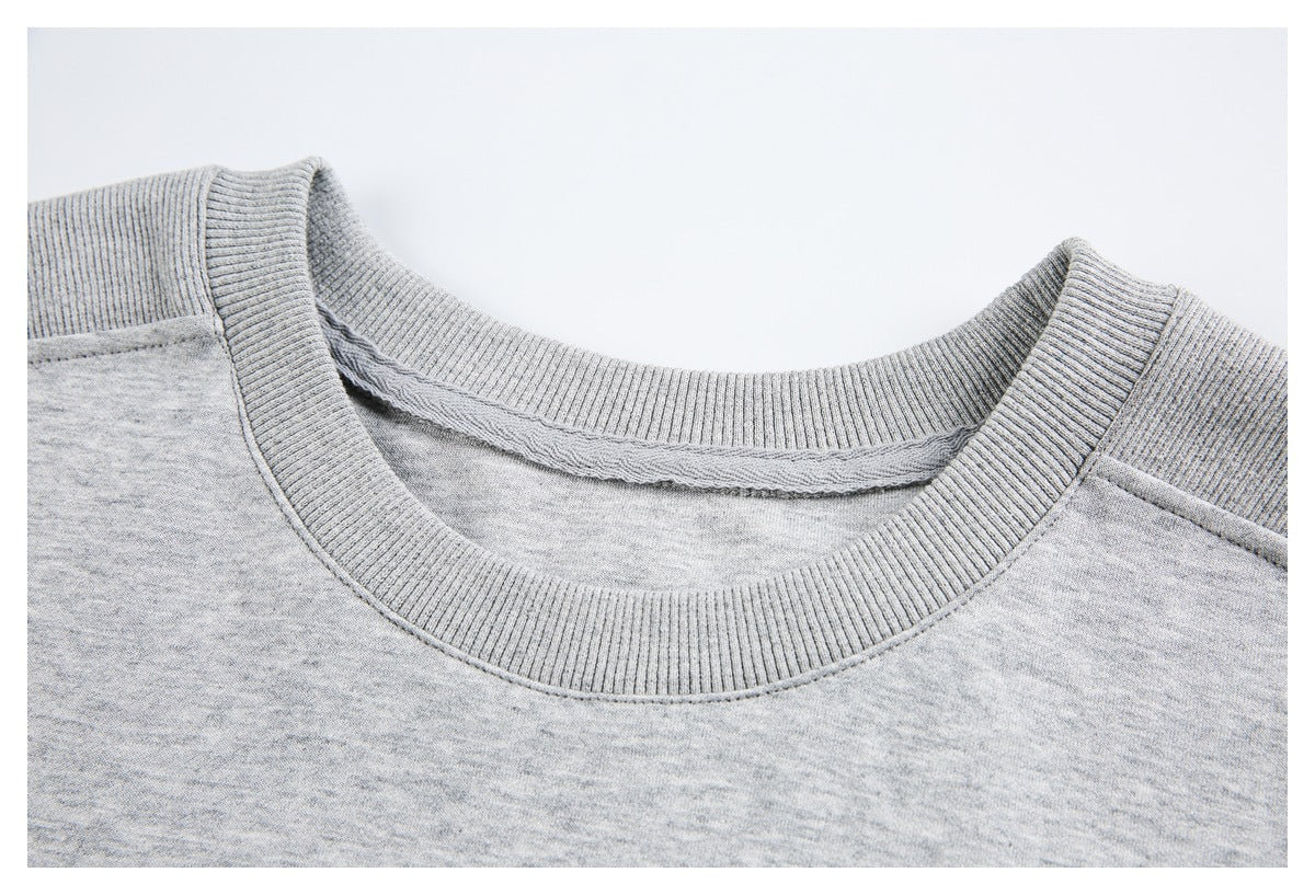 Close-up of a light heather-gray shirt's ribbed crew neck and shoulder seams.