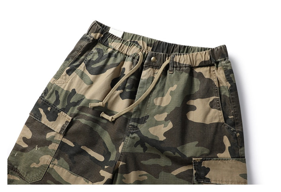 Close view of camouflage cargo shorts showing the elastic waistband, drawstring, front button, and cargo pockets.