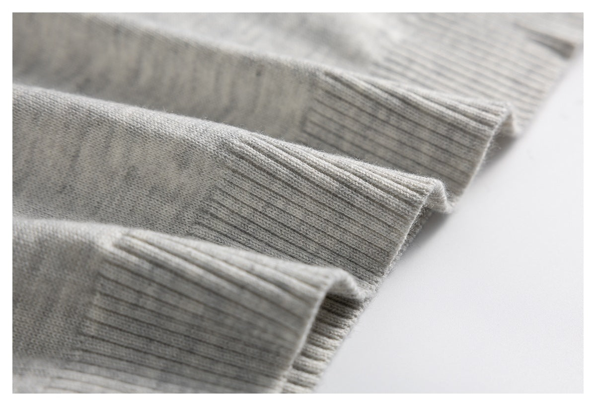 Close-up of light gray knit sweater fabric and layered ribbed cuffs.