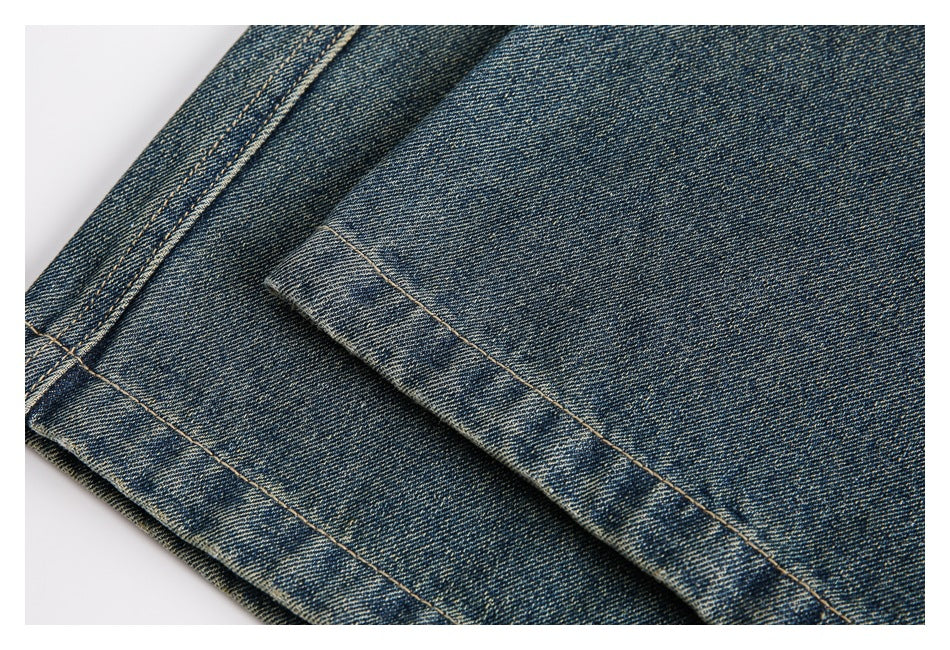 Close-up of a stitched hem on blue washed denim trousers.