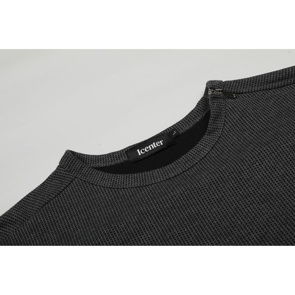 Close-up of a charcoal waffle-knit shirt neckline with a small zipper and sewn-in neck label.