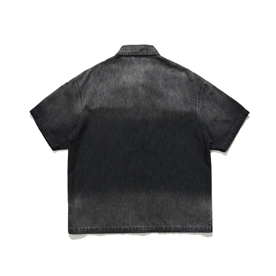 Back view of a black denim short-sleeve shirt with a pointed collar and a plain panel.