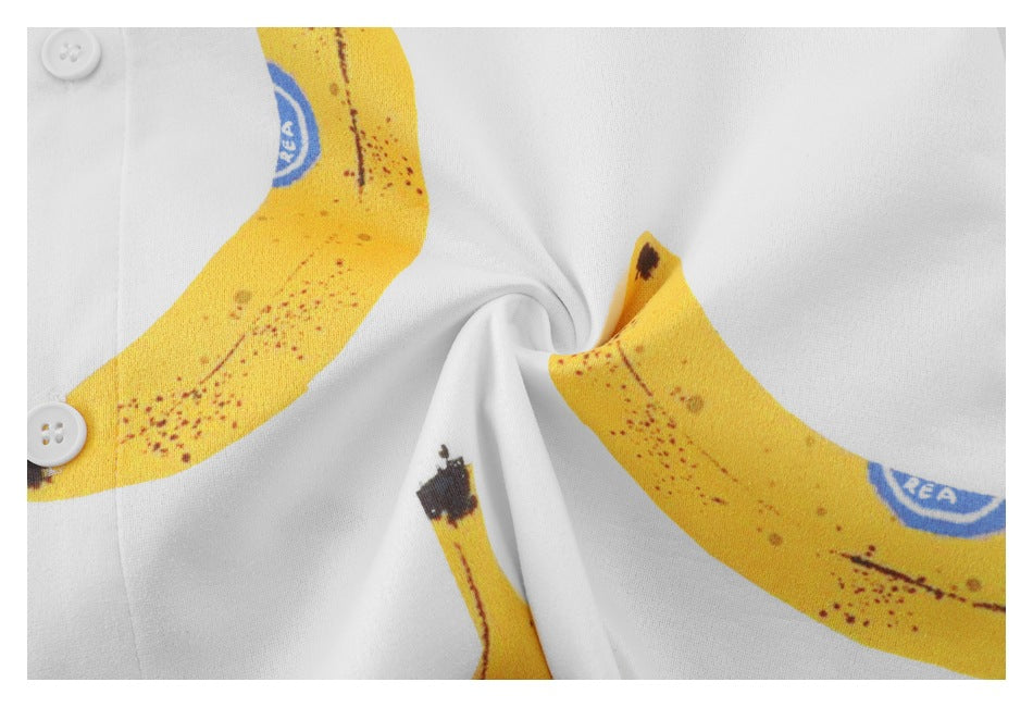 Close-up of the white shirt fabric and banana print beside two white buttons.