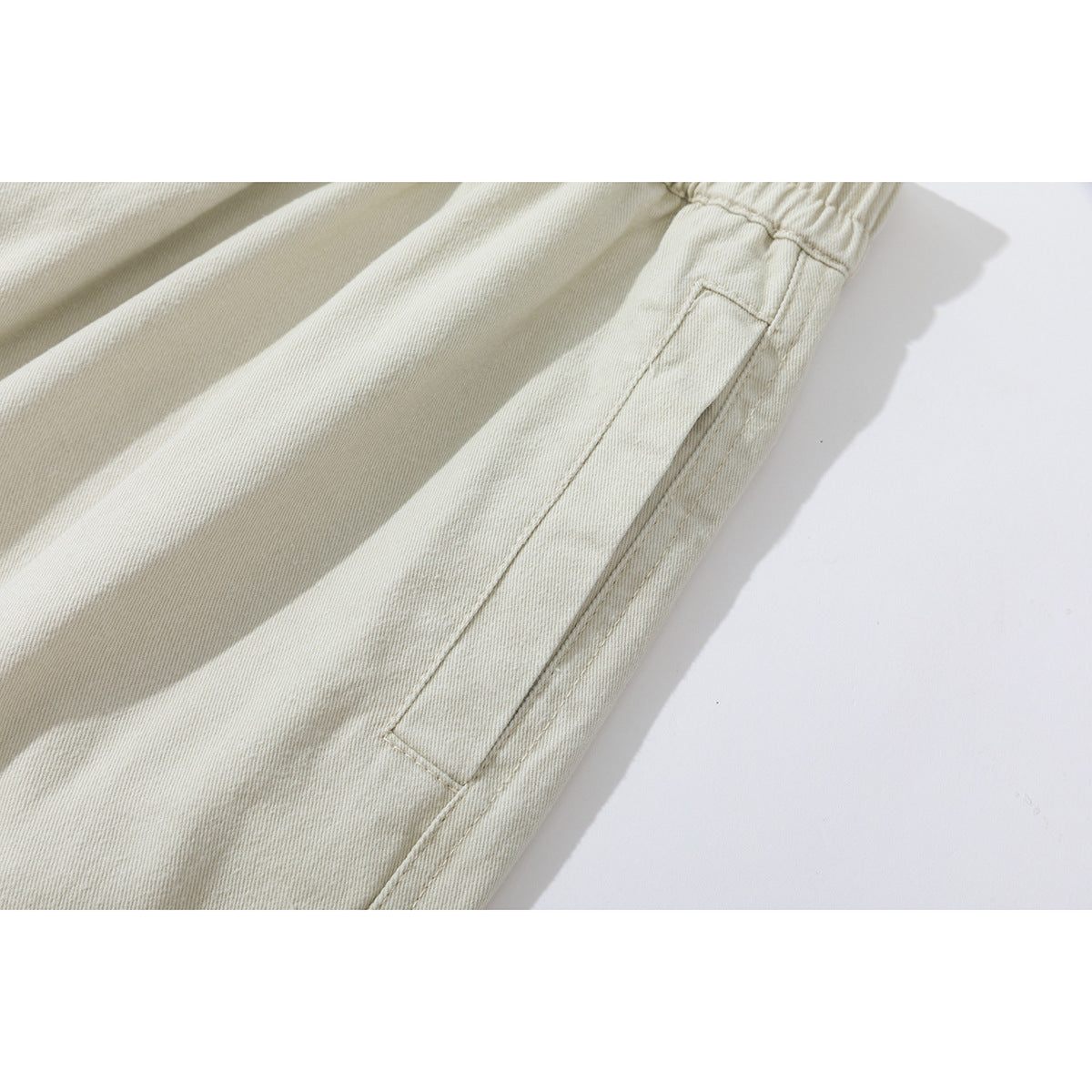 Close-up of ivory pants showing a side pocket and the fabric's diagonal weave.