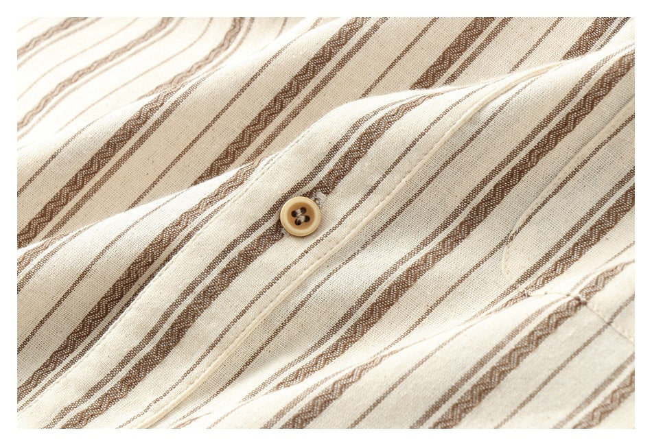 Close-up of a tan button on the placket of cream fabric with brown stripes.