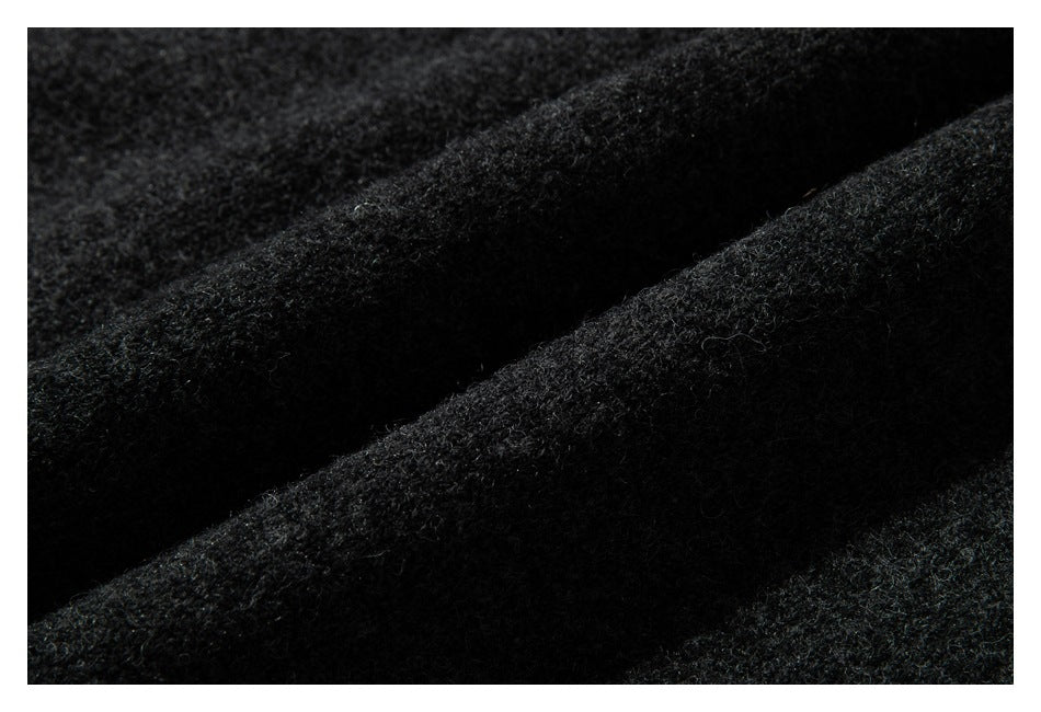Close-up showing the fuzzy, textured dark charcoal knit fabric of the sweater.