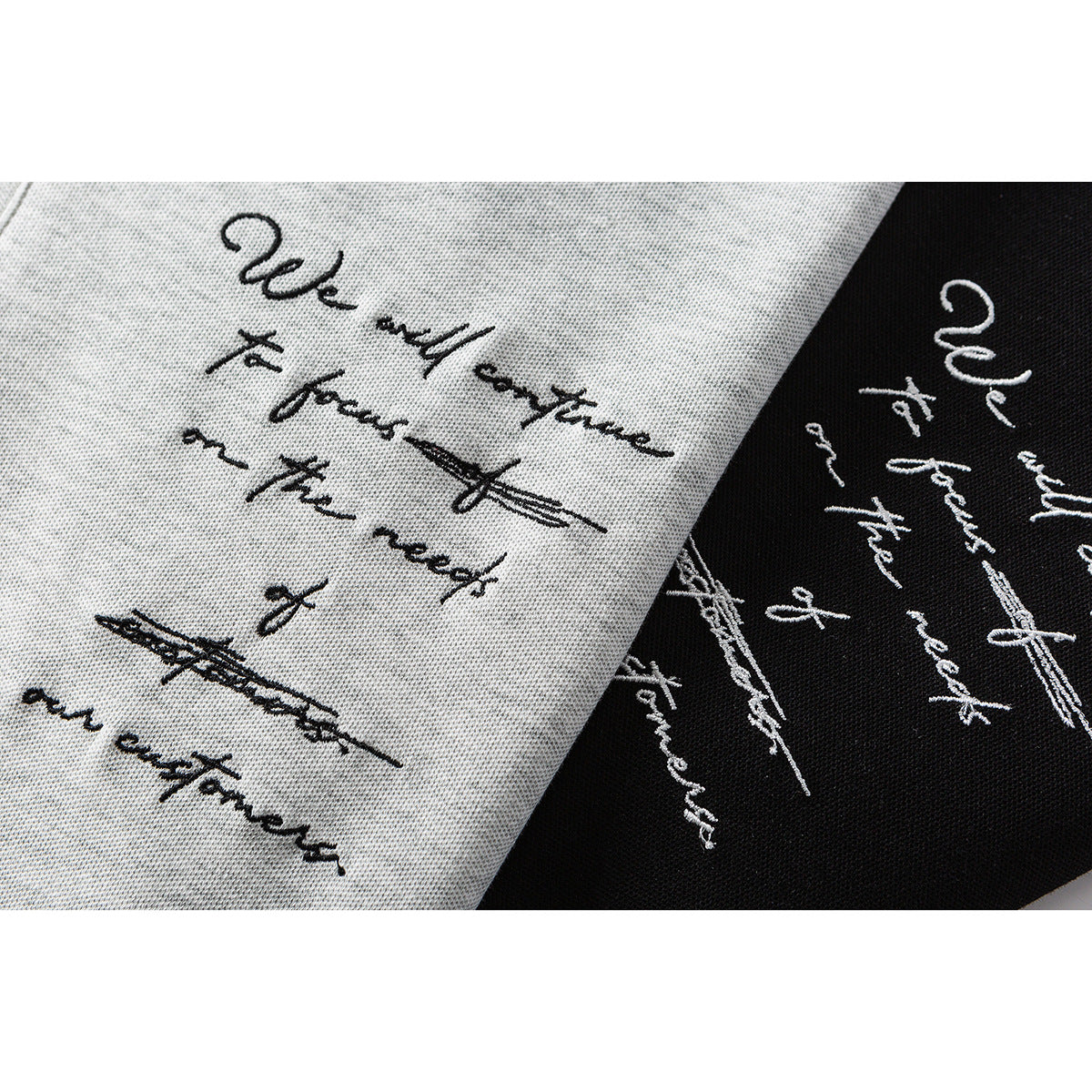 Close-up of black cursive text and crossed-out marks printed on light gray and black shirt fabric.